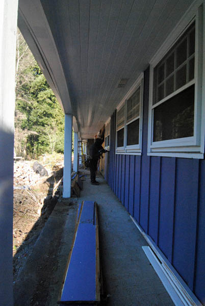 Workers begin to remove siding at the front porch in preparation for the new windows and front door.