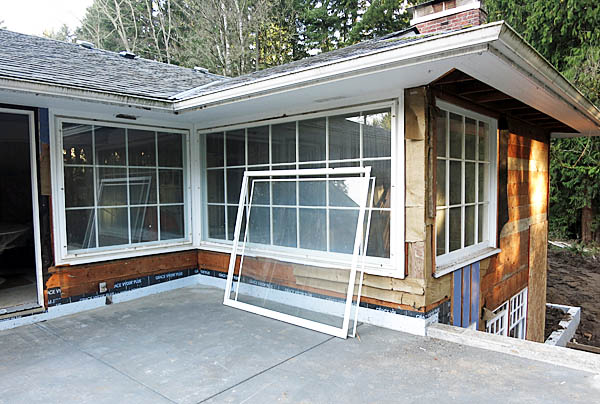 This is an exterior view of the dining room and one living room window. The dining room is on the left. The living room is on the right. The storm window for the dining room window has already been removed in this photo and is leaning against the house.