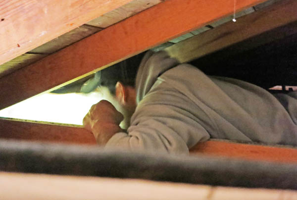 One guy crammed himself in the tiny space between the roof and wall in order to pry out the vent from above.