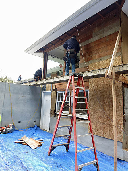 The old window is removed and a worker begins to remove the exterior sheathing.